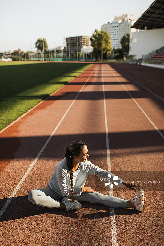 在户外体育场做伸展运动的健壮混血女人图片素材