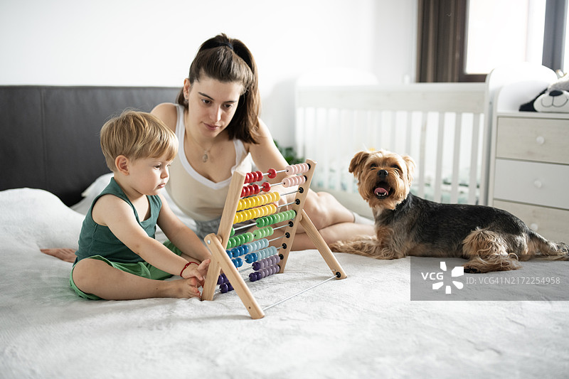单亲母亲和孩子一起玩算盘图片素材