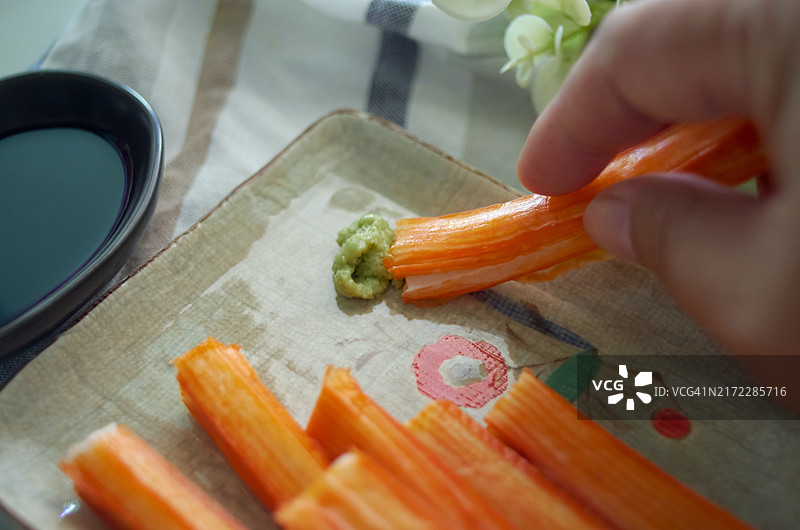 手持蟹肉棒蘸芥末特写，日式料理细节图片素材