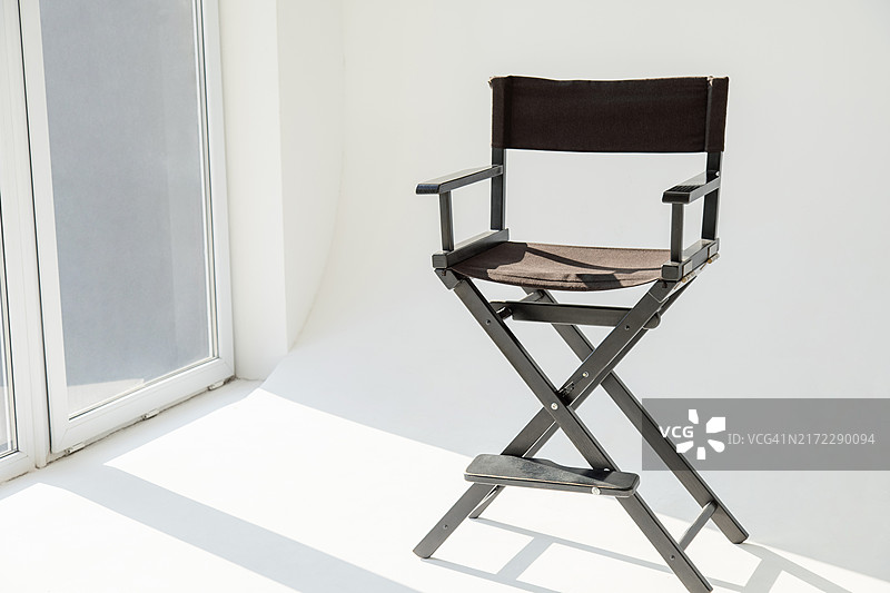 影棚里靠着弧形墙和窗户的折叠椅图片素材