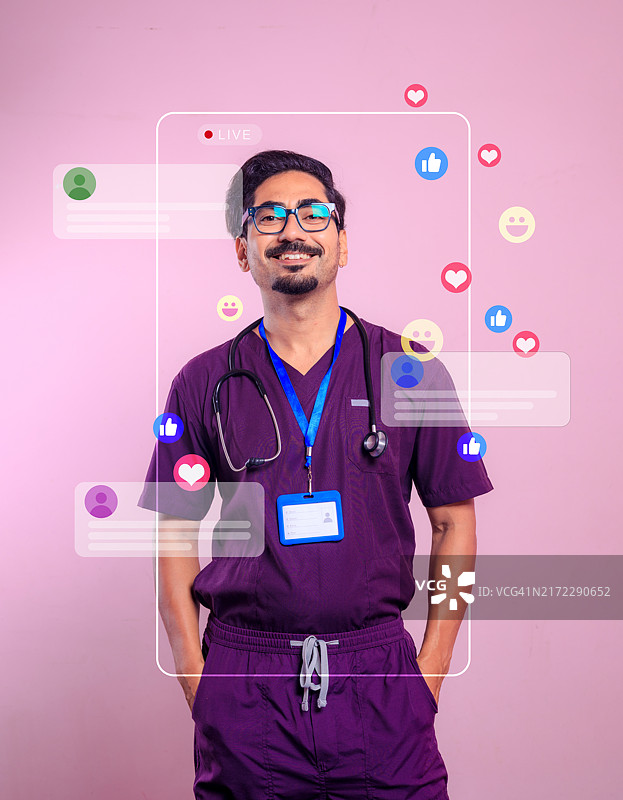 年轻的男医生穿着手术服，对着粉色背景的镜头高兴地微笑图片素材