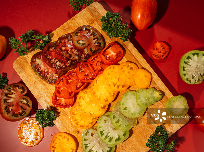 木制砧板上切成圈的不同颜色的成熟和未成熟的西红柿图片素材