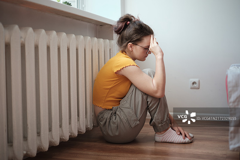 悲伤的青少年，放学后疲惫地坐在地板上图片素材