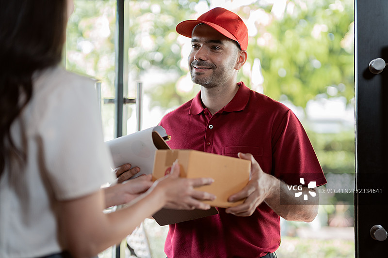 男人送货员在家中给顾客送包裹图片素材