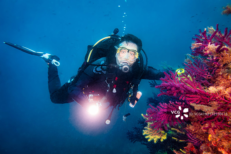 在梅德斯群岛海洋保护区彩色珊瑚附近浮潜的潜水员图片素材
