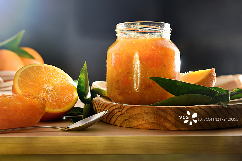 长凳上的橙子果酱罐和深色背景图片素材