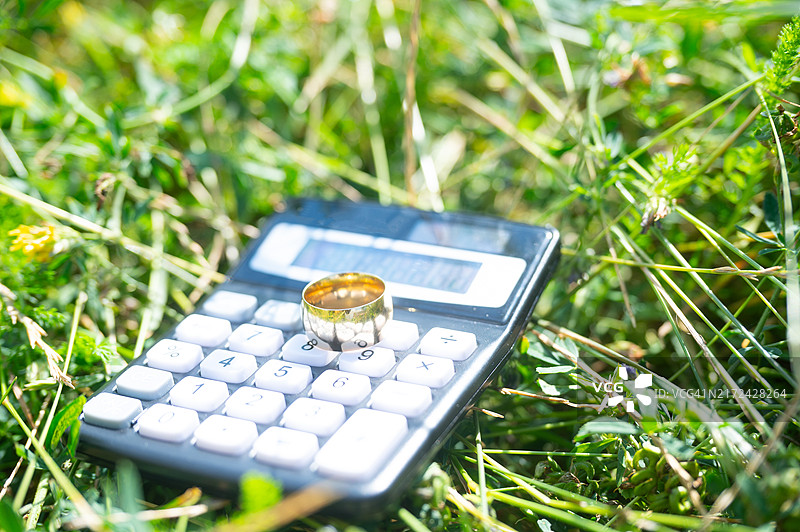草地上的计算器上放着婚戒图片素材