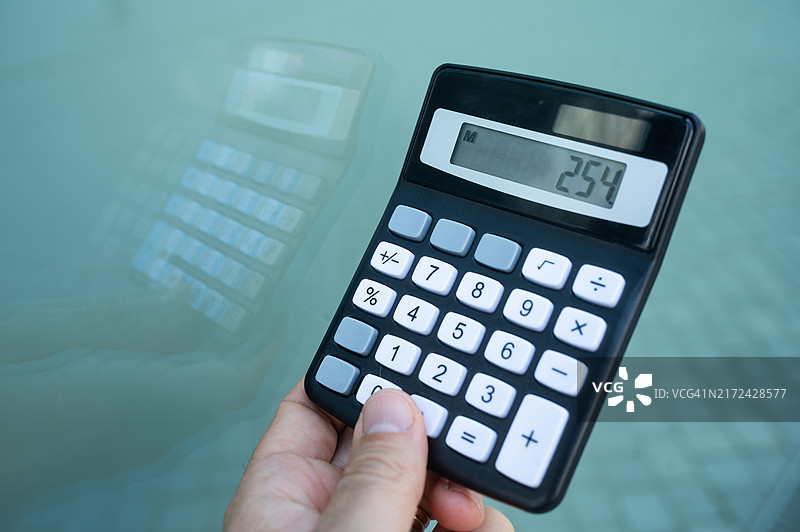 一个人在窗边使用计算器图片素材