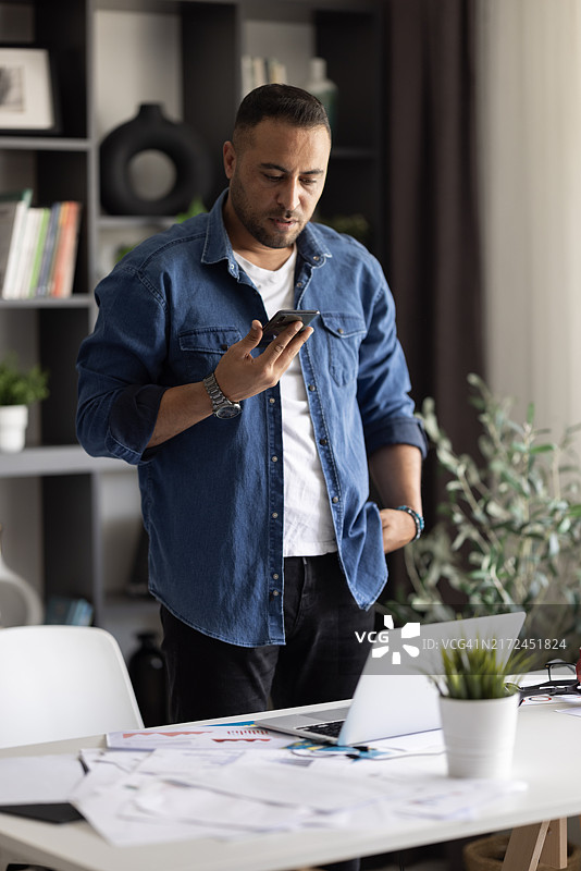 商务生活方式。一个黑发的年轻专业帅气商人在办公室的窗边站着。图片素材