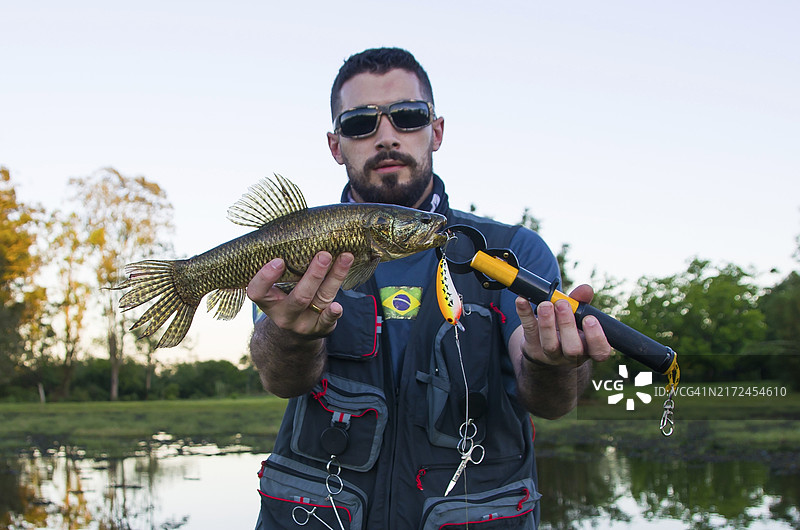 渔民展示用人造鱼饵捕获的鱼，南美牙鱼图片素材