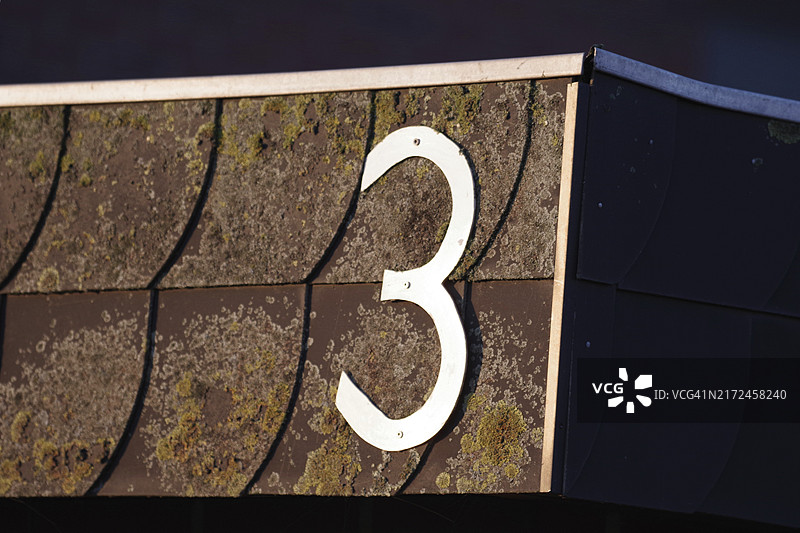 风化外墙上的金属数字3门牌号图片素材