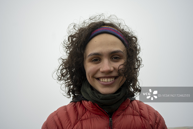 雾天戴发带和羽绒服的年轻女人，微笑，波阿斯火山国家公园，位于哥斯达黎加阿拉胡埃拉省中美洲高地图片素材