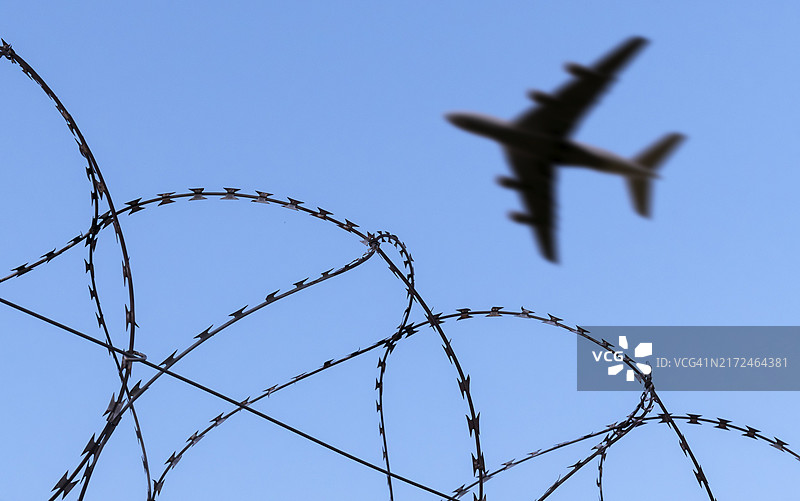 驱逐非法移民的示意图：飞机飞过带刺铁丝网图片素材