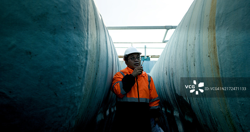 机械工程师在建筑工地操作笔记本电脑和蓝图图片素材