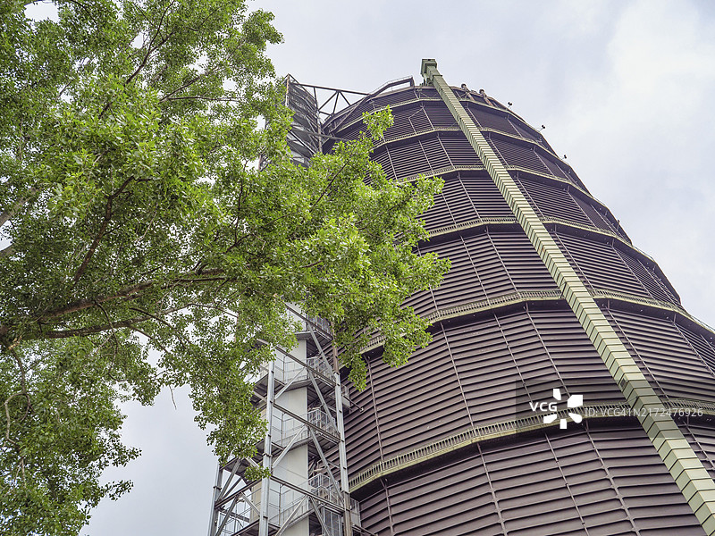 多云天空下的树旁边的工业建筑，奥伯豪森，鲁尔区，德国，欧洲图片素材