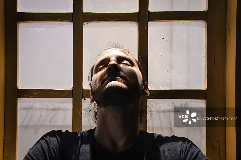 男人沐浴在阳光下，闭着眼睛，表情放松图片素材