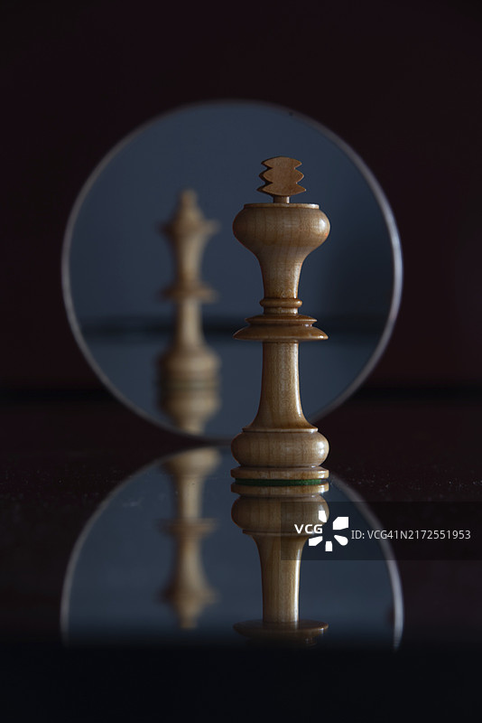 镜中红后棋子的倒影，前方是清晰的红王棋子，象征权力、关系、冲突图片素材