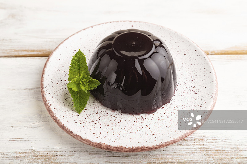 白色木质背景上的黑加仑葡萄果冻，侧视特写图片素材