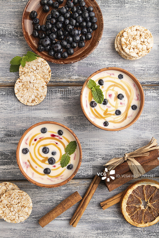 灰色木质背景黏土碗越桔焦糖酸奶图片素材