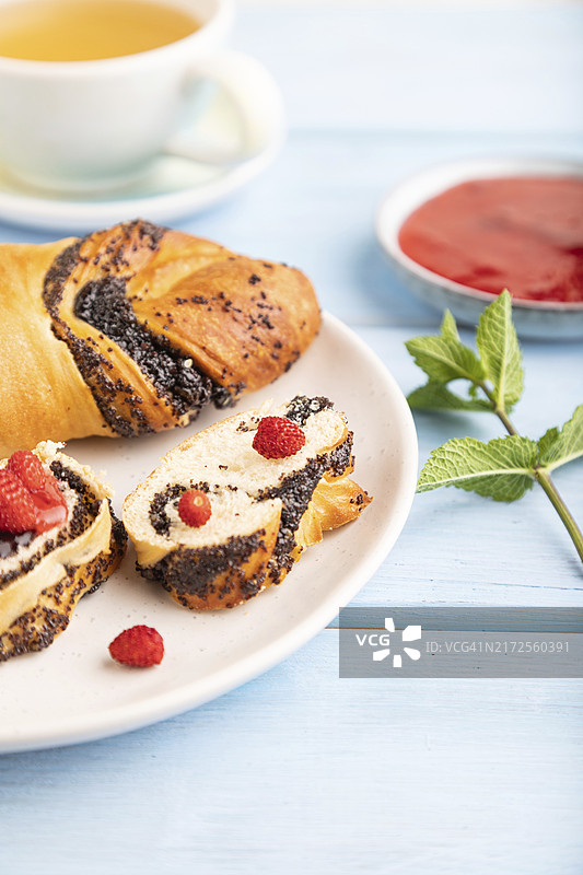 蓝色木质背景上的自制草莓酱甜面包和绿茶，侧视图，特写，选择性聚焦图片素材