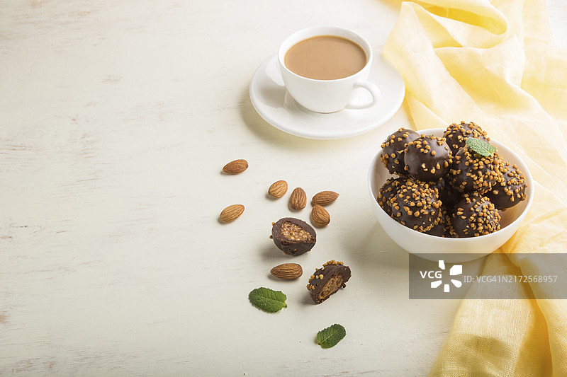 白色木纹背景上的杏仁巧克力焦糖球和咖啡图片素材
