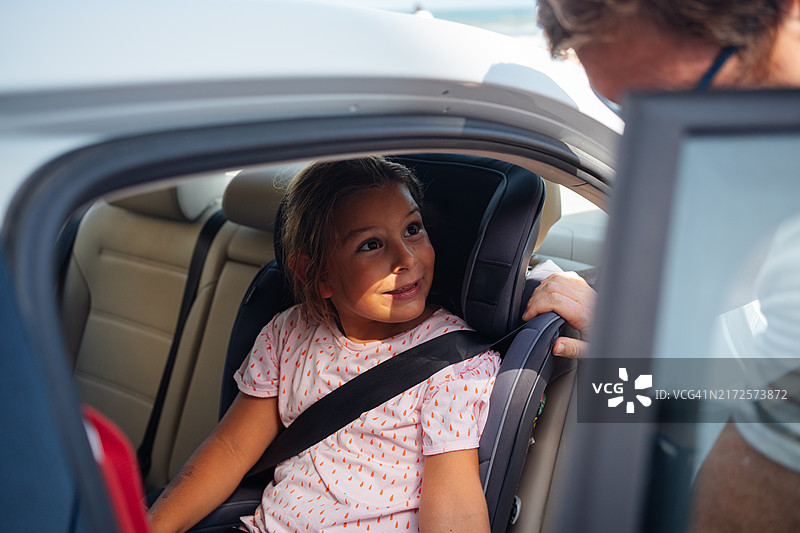 父亲正在把女儿放进安全座椅。图片素材