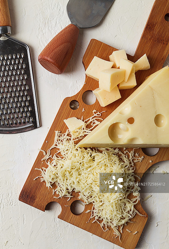 砧板上的马斯丹碎奶酪、磨碎器和奶酪刀，特写图片素材