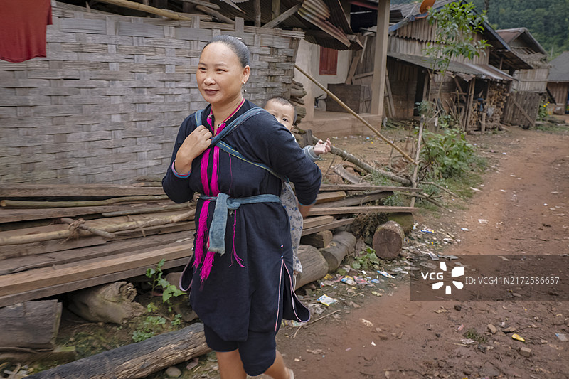 老挝北部村庄里背着婴儿的母亲图片素材