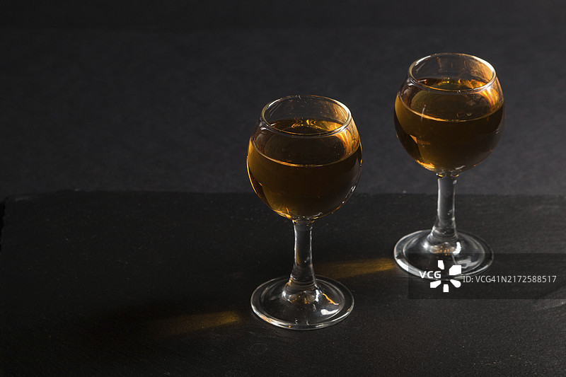 黑色石板上的琥珀色威士忌和焦糖糖果图片素材
