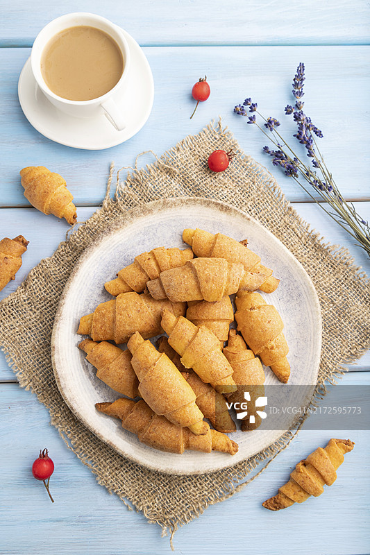 蓝色木质背景上手工贝果卷与咖啡，搭配亚麻纺织品图片素材