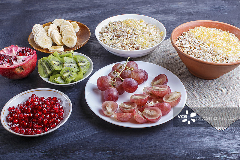 黑木背景上的什锦早餐拼盘：葡萄、猕猴桃、石榴、香蕉图片素材