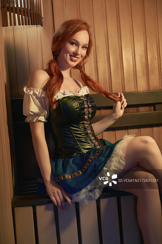 身穿时尚连衣裙坐在椅子上看向镜头的迷人年轻女性侧视图图片素材