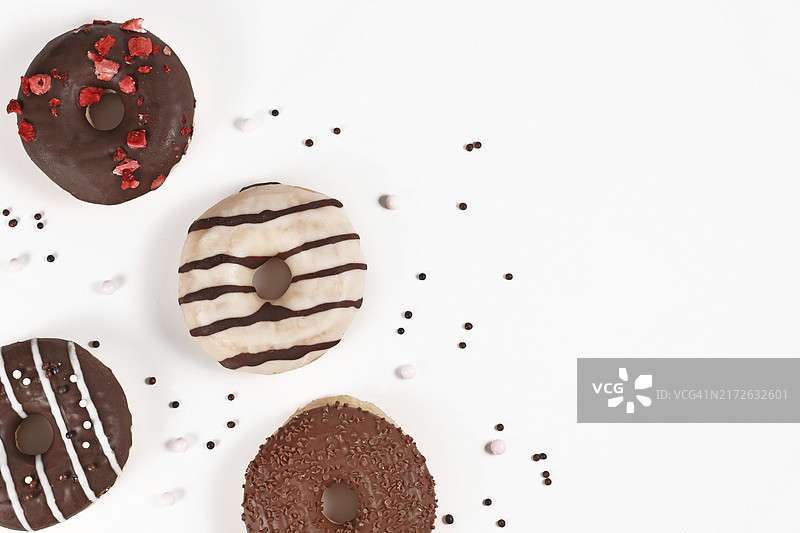 白色背景角落里带有巧克力釉和糖屑的甜甜圈图片素材