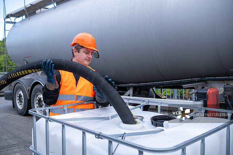 一名技术人员将油从油轮转移到1000升的IBC大容器中。图片素材