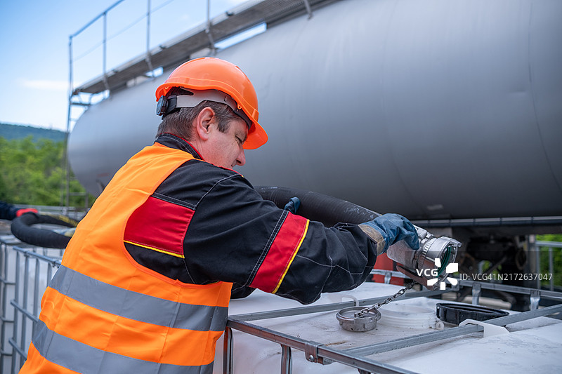 一名技术人员将油从油轮转移到1000升的IBC大容器中。图片素材