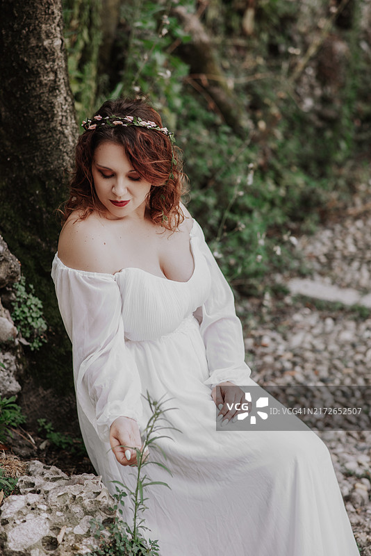 红发年轻女子坐在树干上玩树叶图片素材