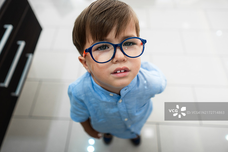 戴眼镜的悲伤儿童抬头哭泣，脸上挂着泪痕图片素材