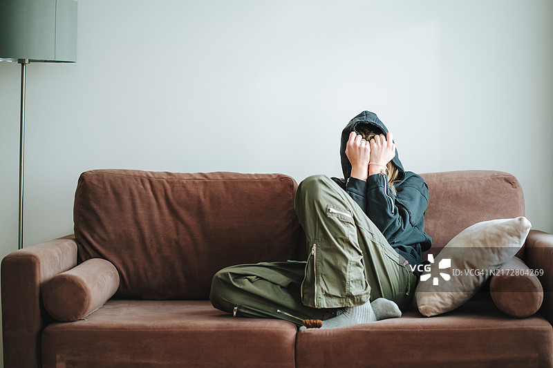 悲伤的女人：独自一人在沙发上掩面哭泣的女性图片素材