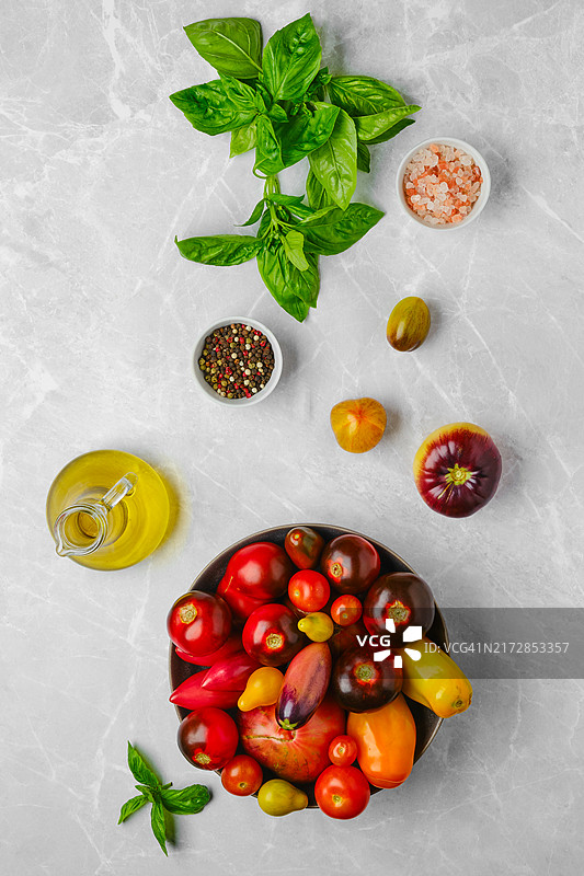 大理石背景上的番茄、罗勒和香料的垂直构图图片素材