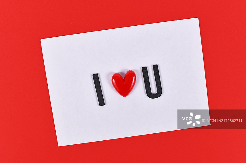 情人节文字“我爱你”，用白色卡片上的心形拼写，红色背景图片素材