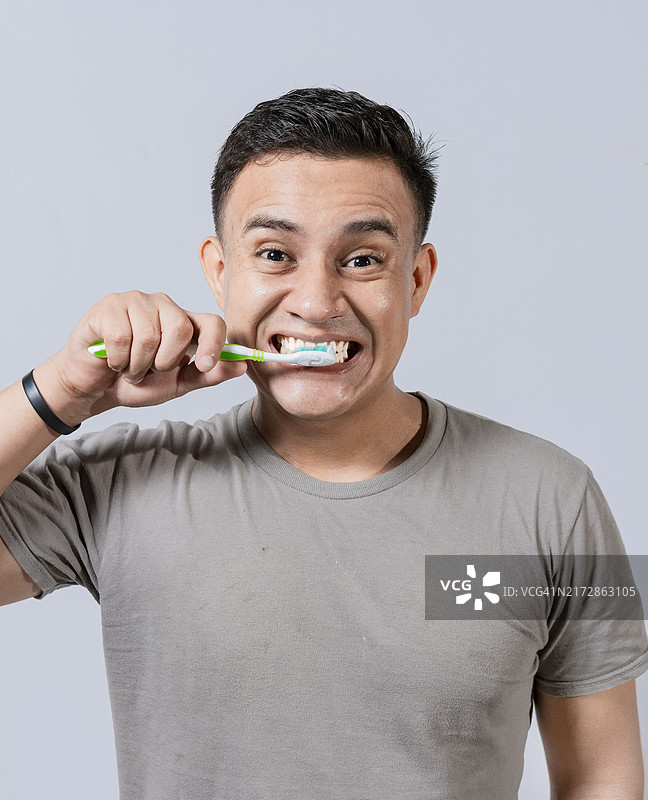 英俊男人刷牙的面部。牙齿护理概念。男人刷牙。口腔和牙齿微笑概念，微笑男人刷牙图片素材