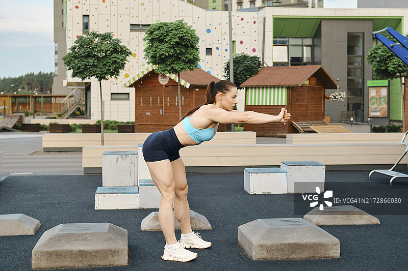早晨，在住宅区的运动区里做弯腰运动的健壮健身女性图片素材