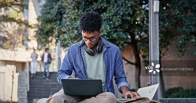 在户外或校园里，大学生使用笔记本电脑阅读书籍学习图片素材