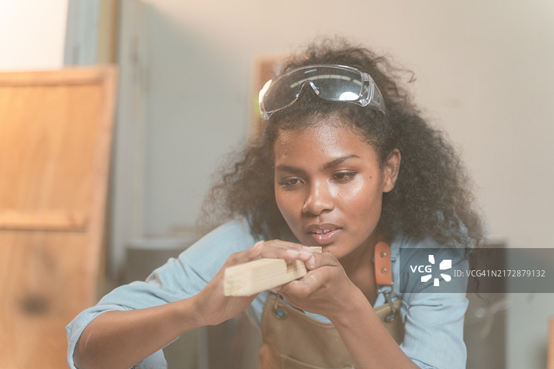 女人戴着安全眼镜和围裙，正在做一个项目图片素材