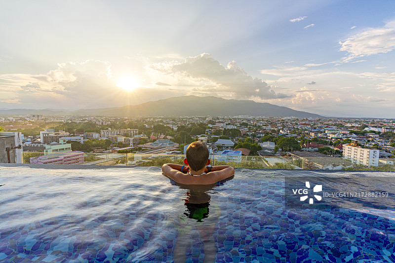 快乐的男孩在无边泳池欣赏日落图片素材