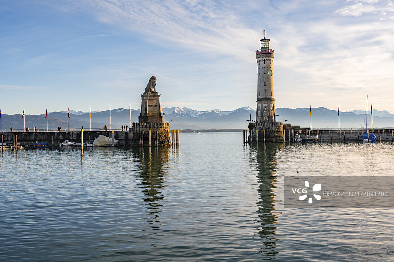 林道港港口入口、新林道灯塔和巴伐利亚狮子雕塑，背景是白雪皑皑的山脉（德国巴伐利亚州康斯坦茨湖林道岛，欧洲）图片素材
