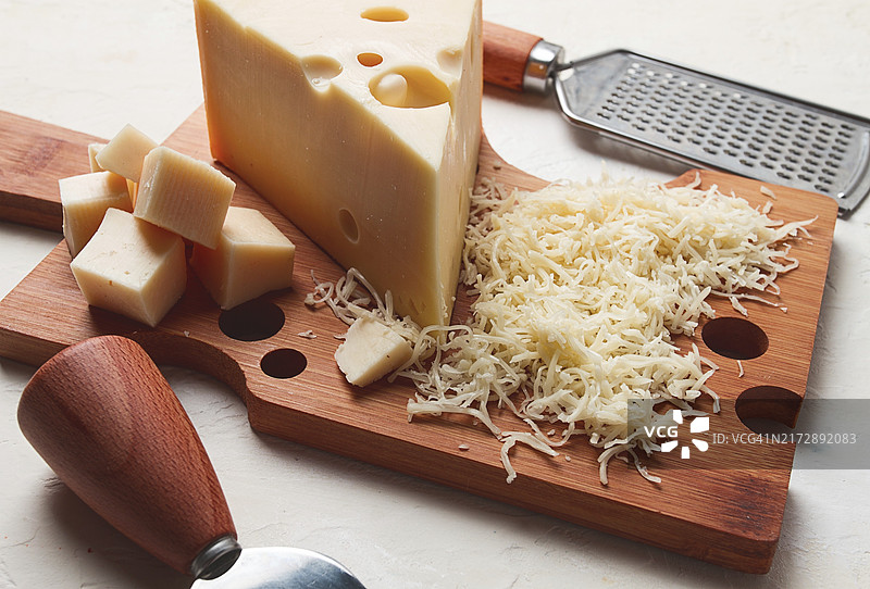 砧板上的马斯丹碎奶酪、磨碎器和奶酪刀，特写图片素材