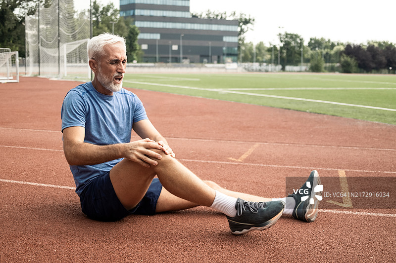 年长的男人跑步时膝盖受伤图片素材