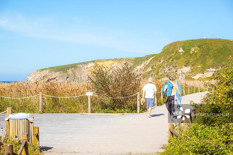 冲浪者走在海滩木板路上图片素材