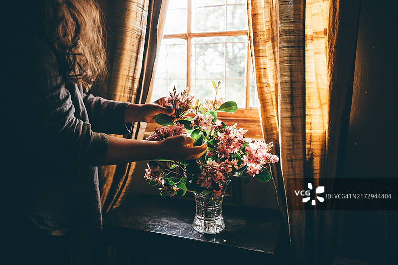 一位女性用野花花束装饰房间。图片素材